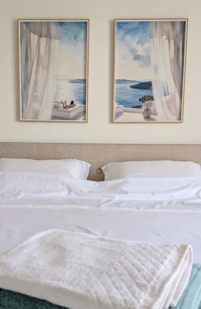Crisp white bedding beneath two watercolour sea prints